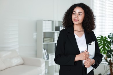 Photo of Professional psychologist with clipboard and pen in office, space for text