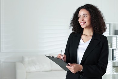 Photo of Professional psychologist with clipboard and pen in office, space for text