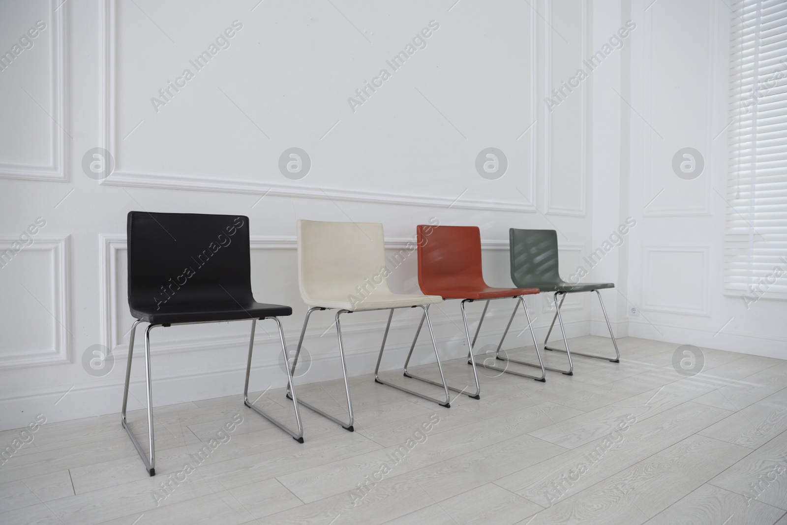 Colorful chairs near white wall in waiting room Photo of Colorful chairs near white wall in waiting room