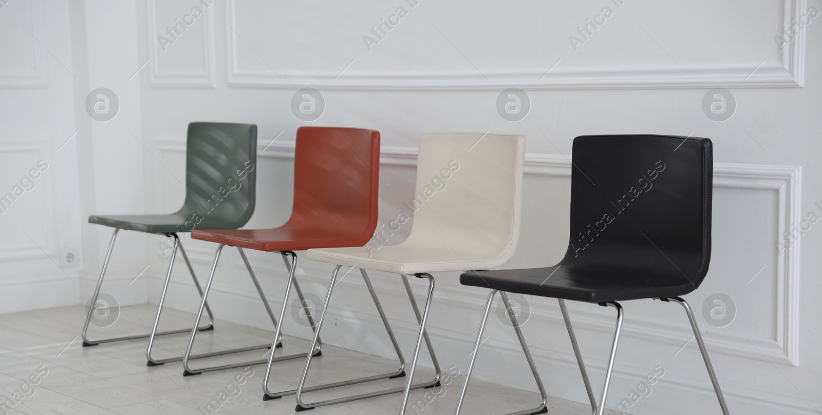 Colorful chairs near white wall in waiting room Photo of Colorful chairs near white wall in waiting room