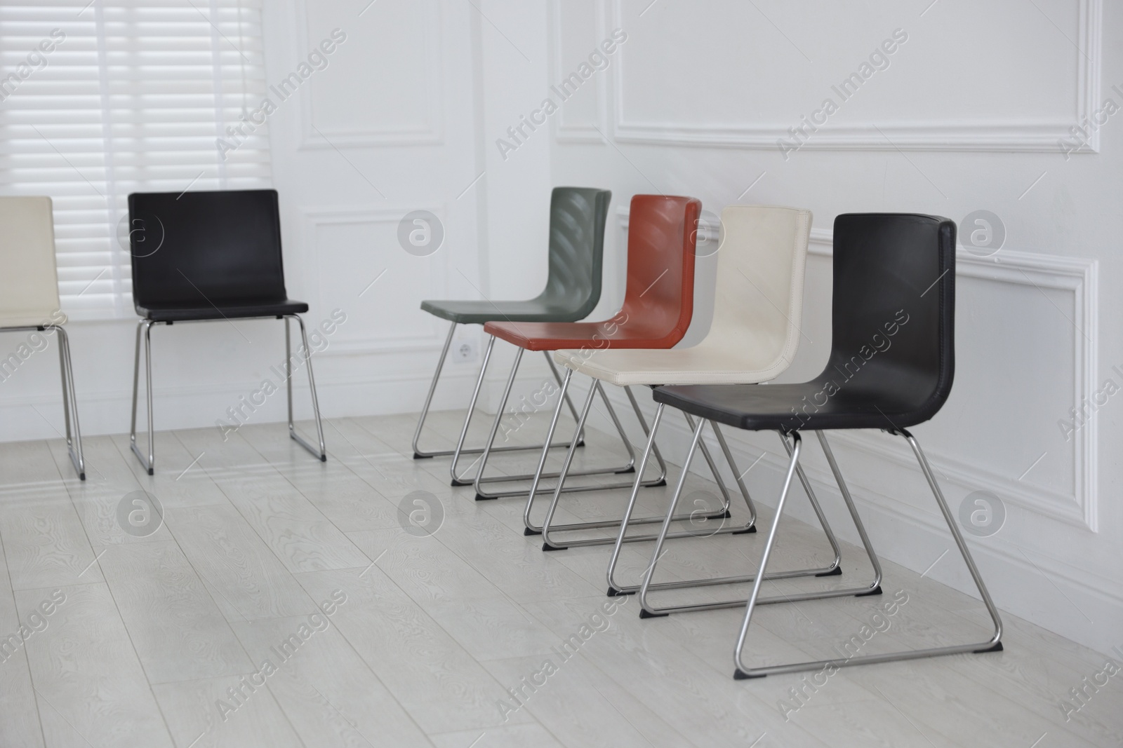 Colorful chairs near white wall in waiting room Photo of Colorful chairs near white wall in waiting room