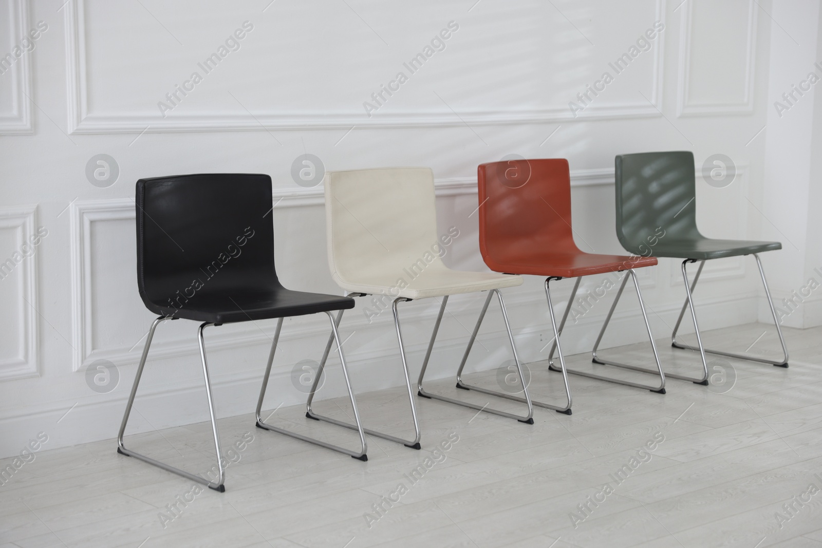 Colorful chairs near white wall in waiting room Photo of Colorful chairs near white wall in waiting room