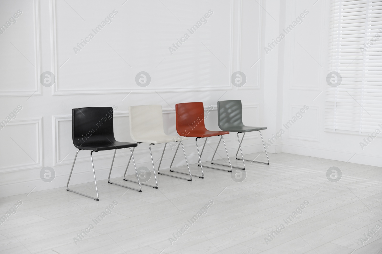 Colorful chairs near white wall in waiting room Photo of Colorful chairs near white wall in waiting room