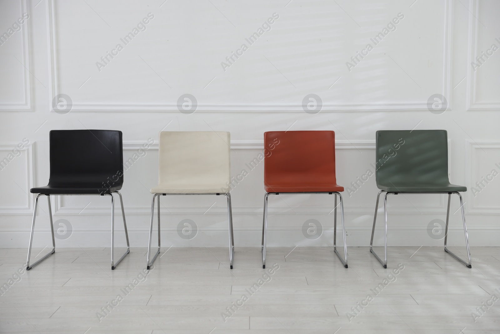 Colorful chairs near white wall in waiting room Photo of Colorful chairs near white wall in waiting room