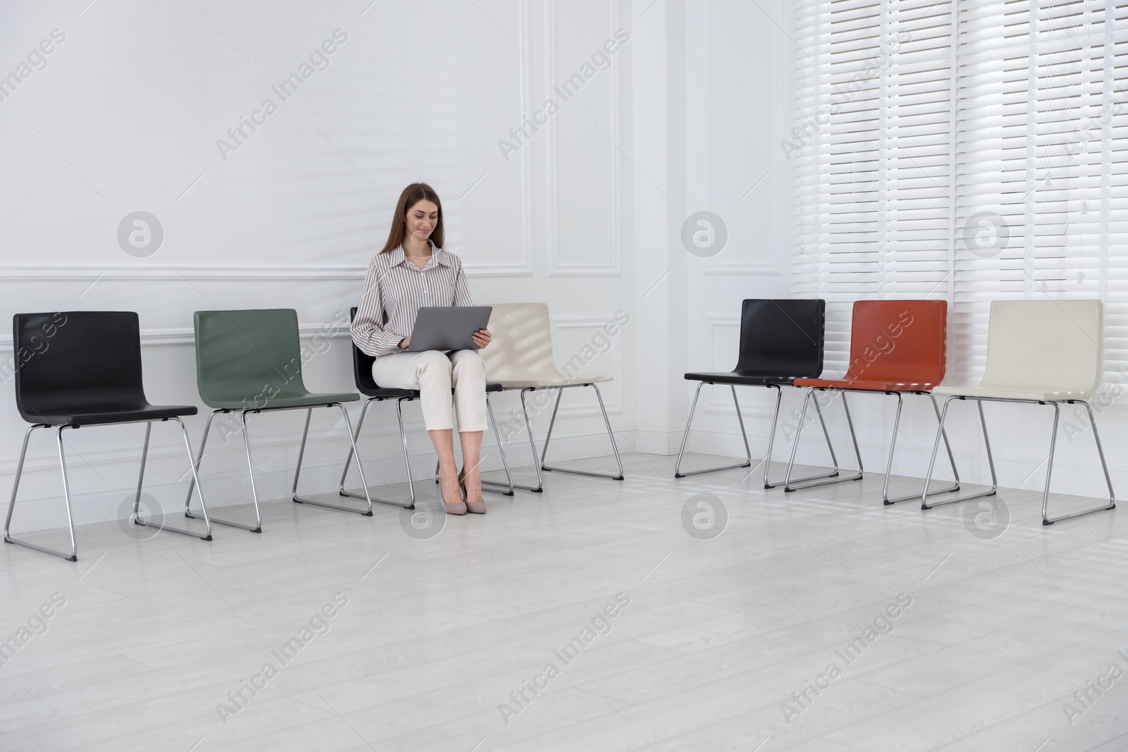Woman with laptop waiting for appointment indoors Photo of Woman with laptop waiting for appointment indoors