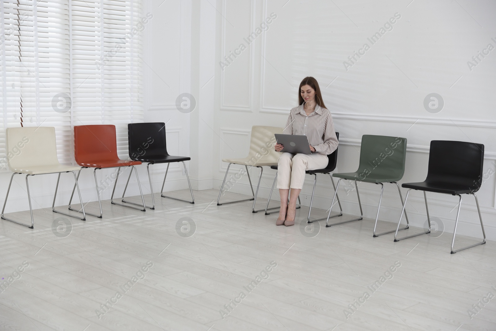 Woman with laptop waiting for appointment indoors Photo of Woman with laptop waiting for appointment indoors
