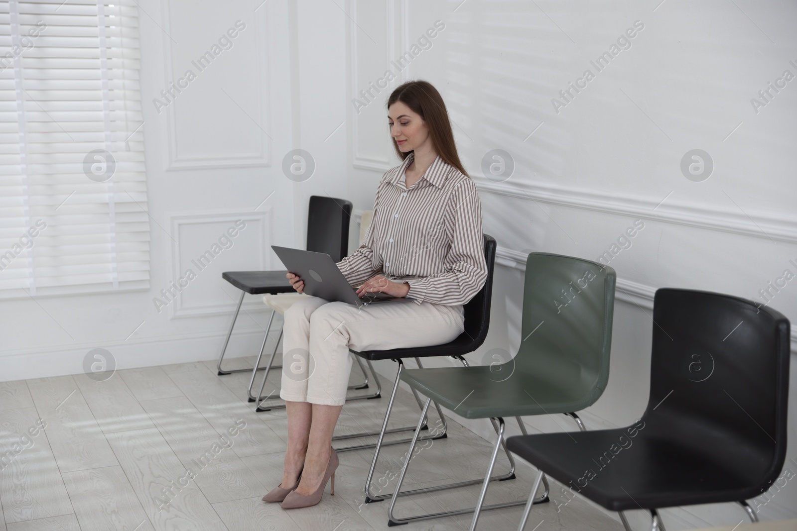 Woman with laptop waiting for appointment indoors Photo of Woman with laptop waiting for appointment indoors