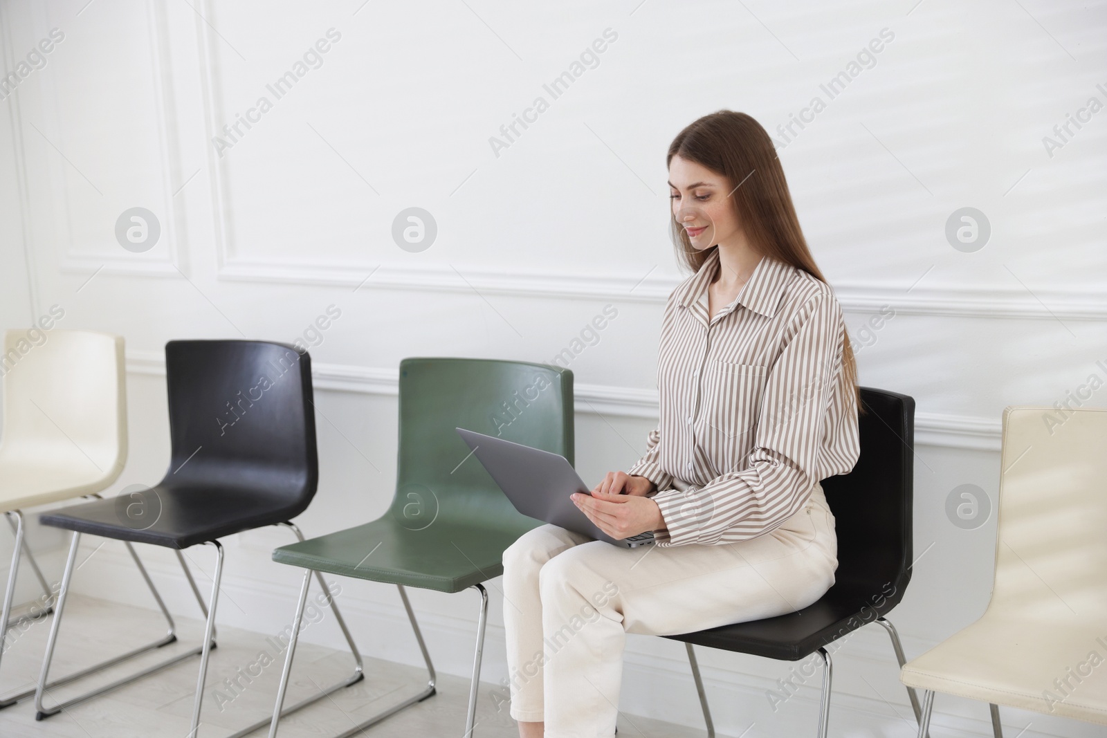 Woman with laptop waiting for appointment indoors Photo of Woman with laptop waiting for appointment indoors