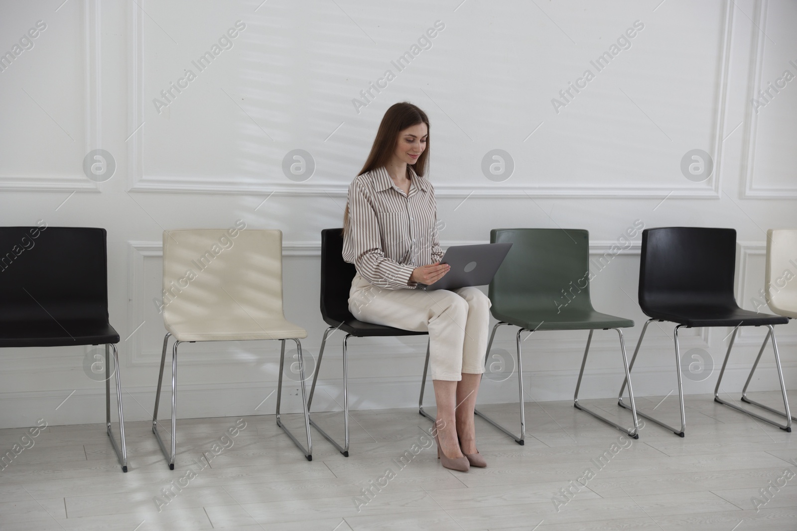 Woman with laptop waiting for appointment indoors Photo of Woman with laptop waiting for appointment indoors