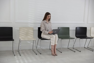 Photo of Woman with laptop waiting for appointment indoors