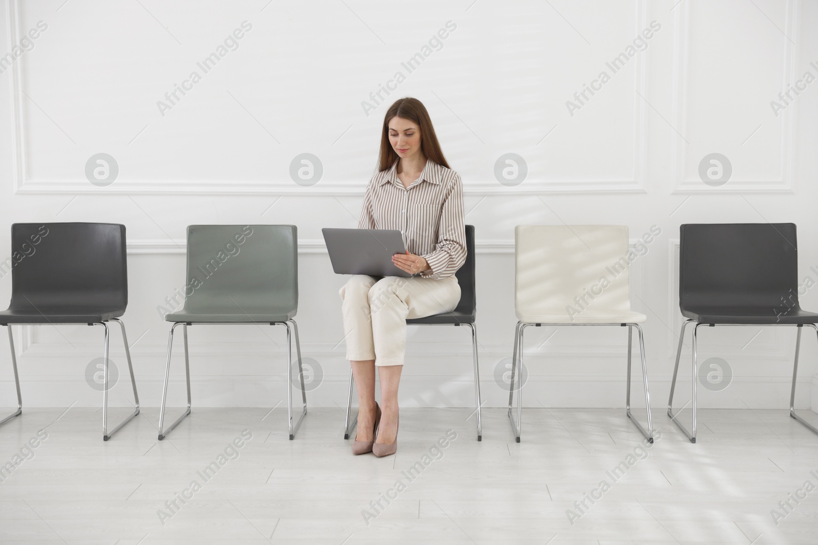 Photo of Woman with laptop waiting for appointment indoors
