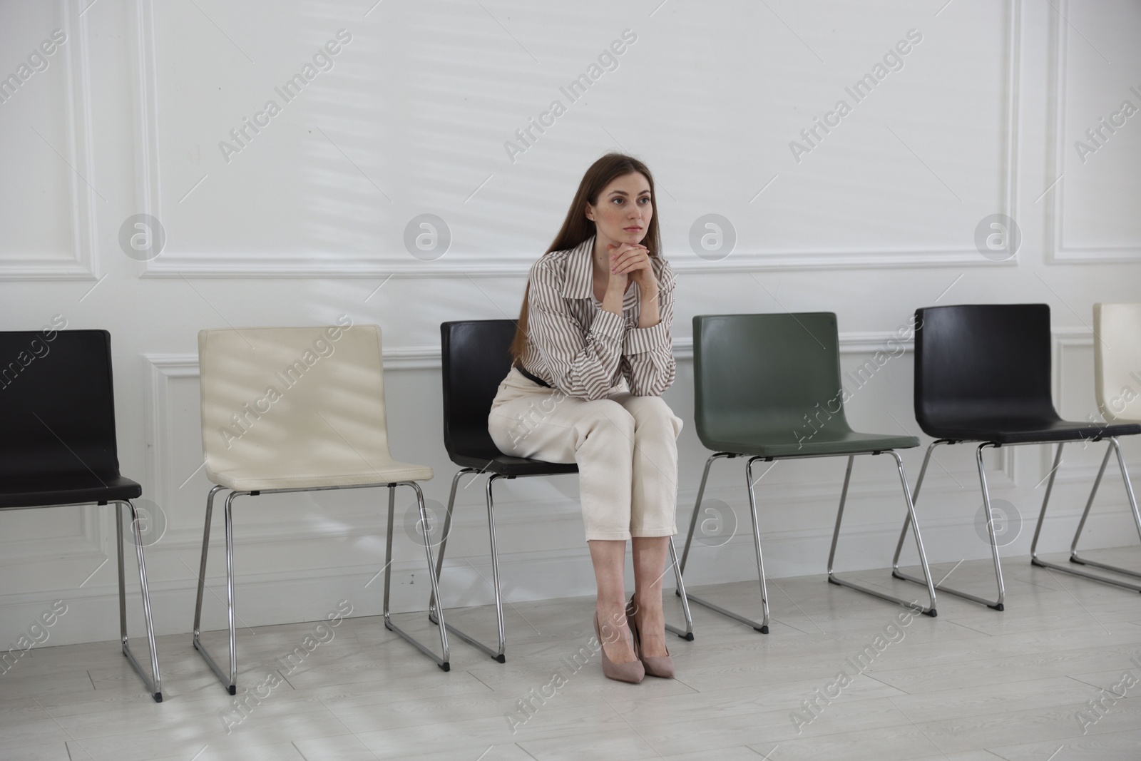 Woman sitting on chair and waiting for appointment indoors Photo of Woman sitting on chair and waiting for appointment indoors