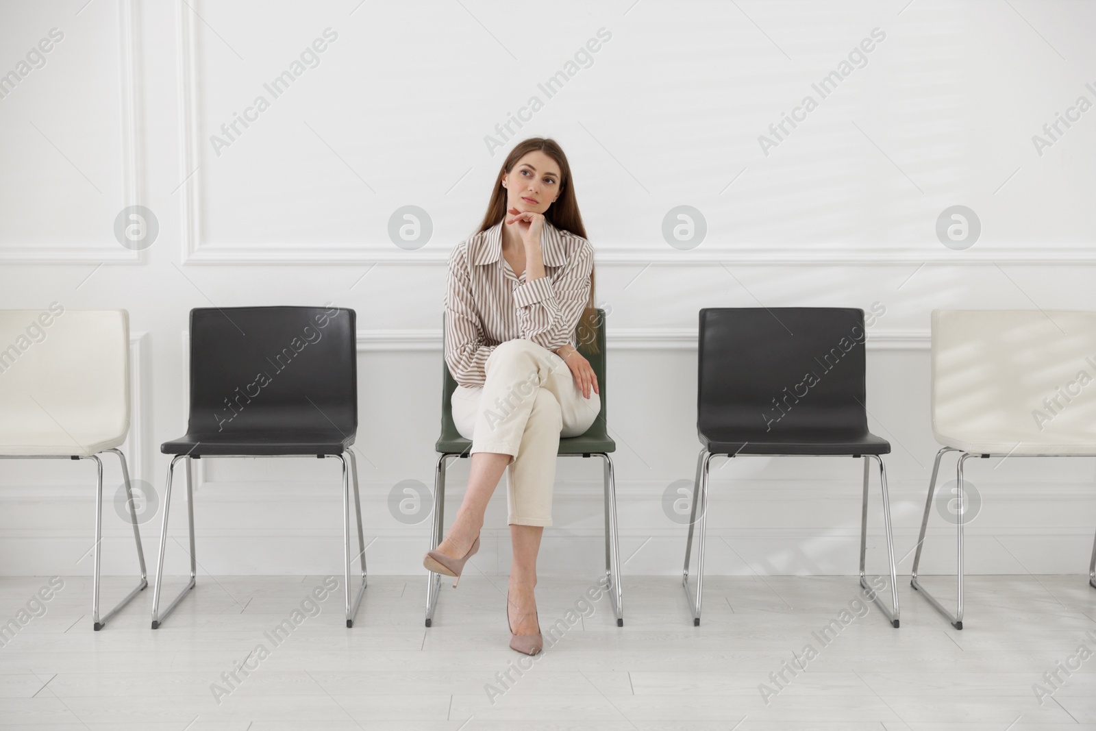 Woman sitting on chair and waiting for appointment indoors Photo of Woman sitting on chair and waiting for appointment indoors
