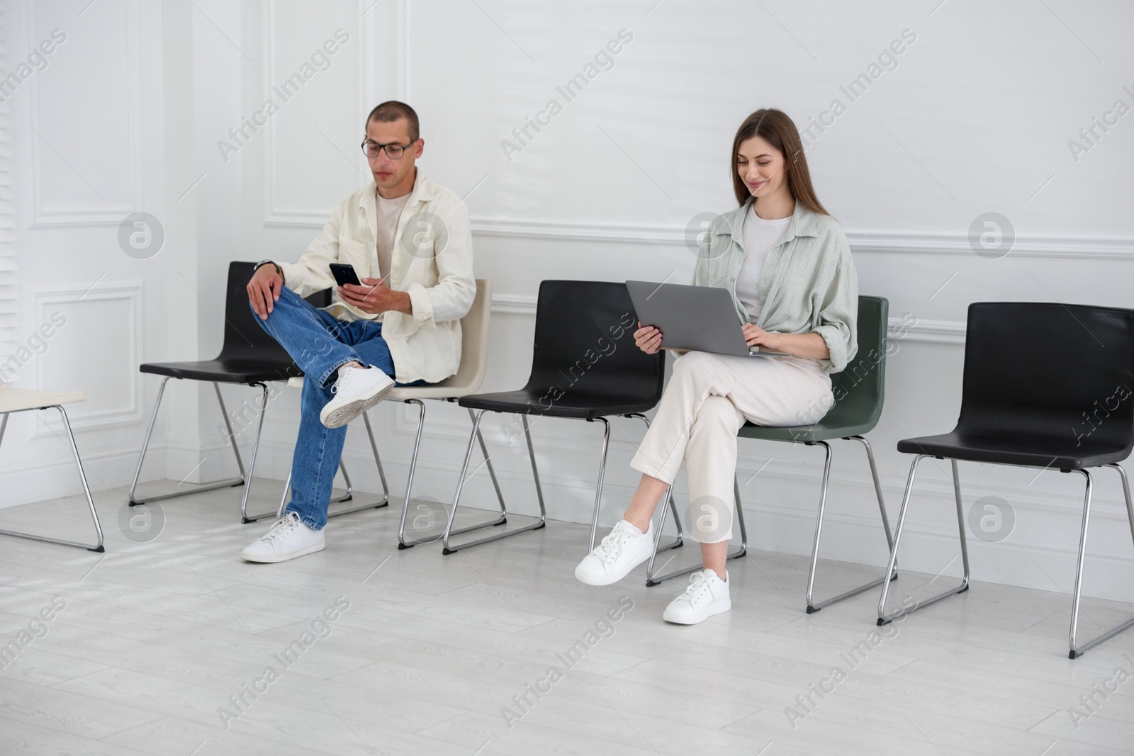 Man and woman waiting for appointment indoors Photo of Man and woman waiting for appointment indoors