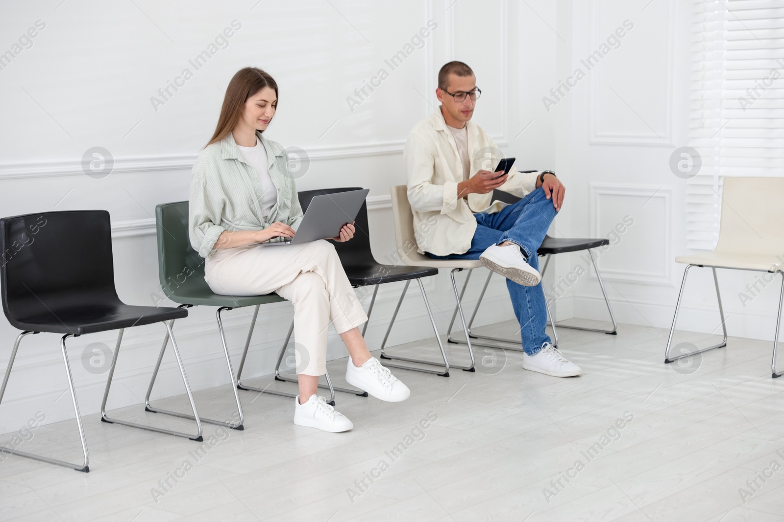 Man and woman waiting for appointment indoors Photo of Man and woman waiting for appointment indoors