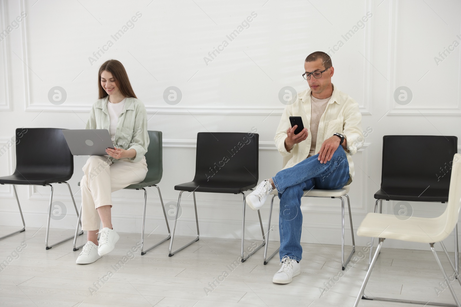 Man and woman waiting for appointment indoors Photo of Man and woman waiting for appointment indoors