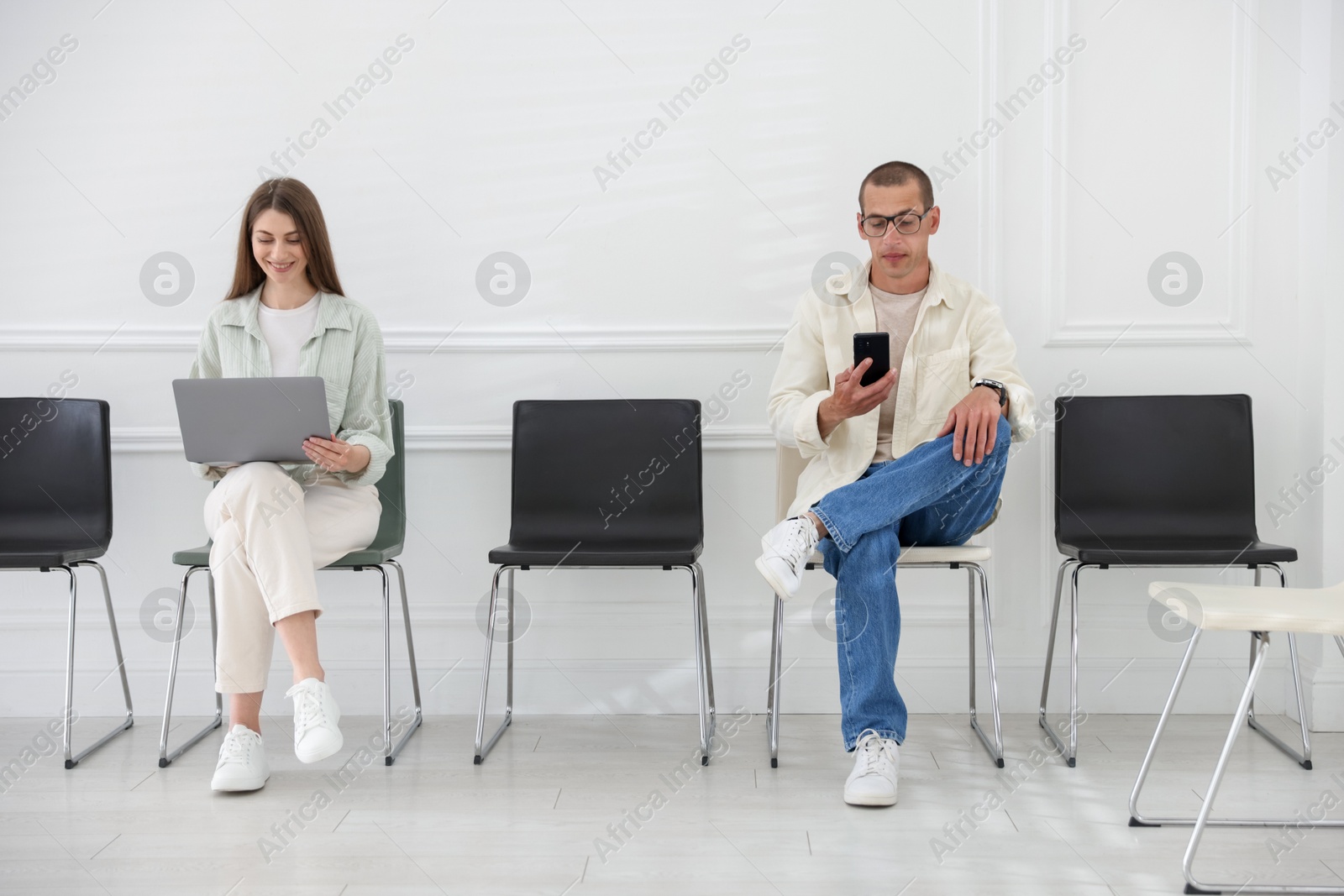 Man and woman waiting for appointment indoors Photo of Man and woman waiting for appointment indoors