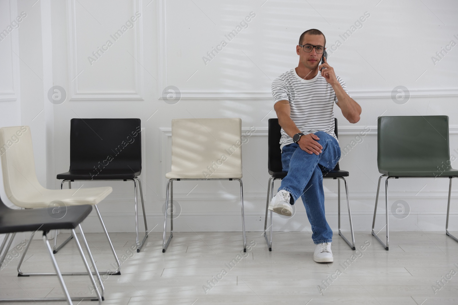 Man talking on smartphone while waiting for appointment indoors Photo of Man talking on smartphone while waiting for appointment indoors