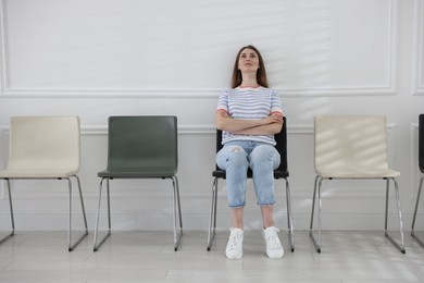 Photo of Woman sitting on chair and waiting for appointment indoors