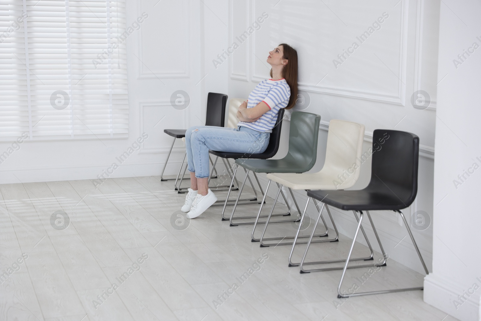 Woman sitting on chair and waiting for appointment indoors Photo of Woman sitting on chair and waiting for appointment indoors
