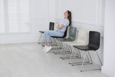 Photo of Woman sitting on chair and waiting for appointment indoors
