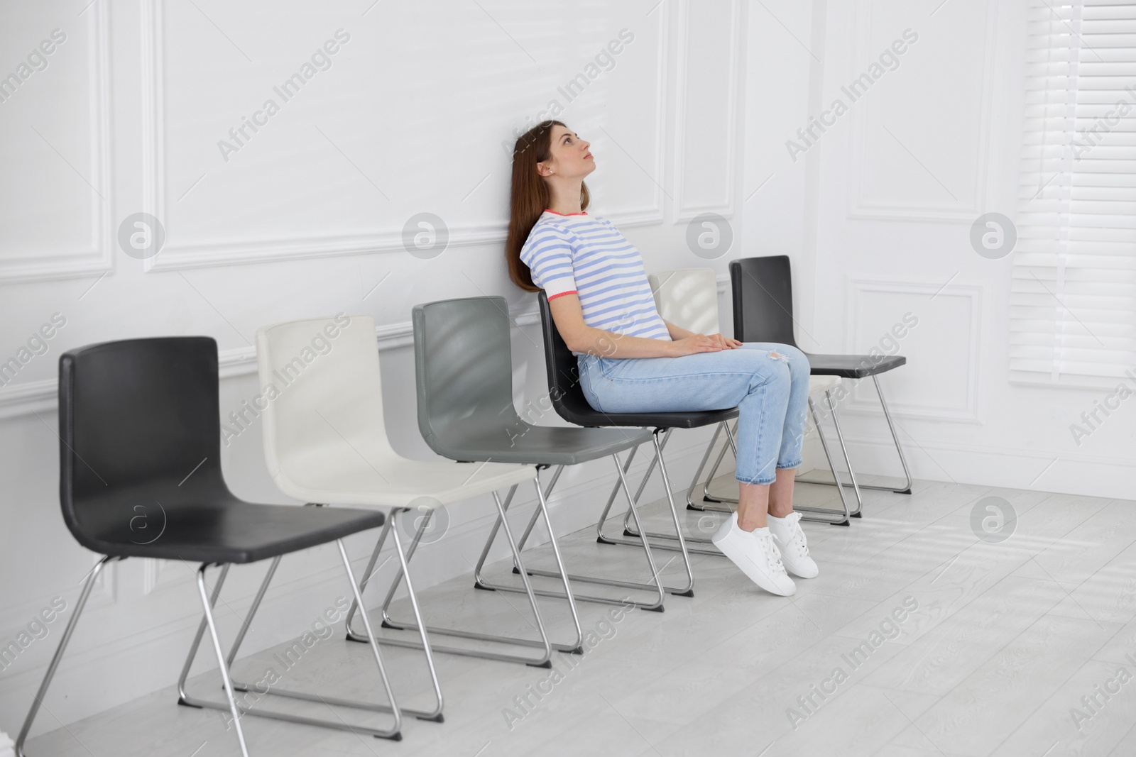 Woman sitting on chair and waiting for appointment indoors Photo of Woman sitting on chair and waiting for appointment indoors