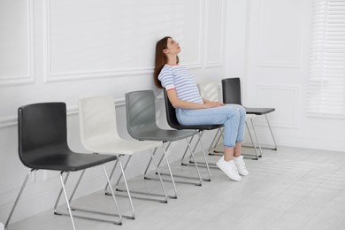 Photo of Woman sitting on chair and waiting for appointment indoors