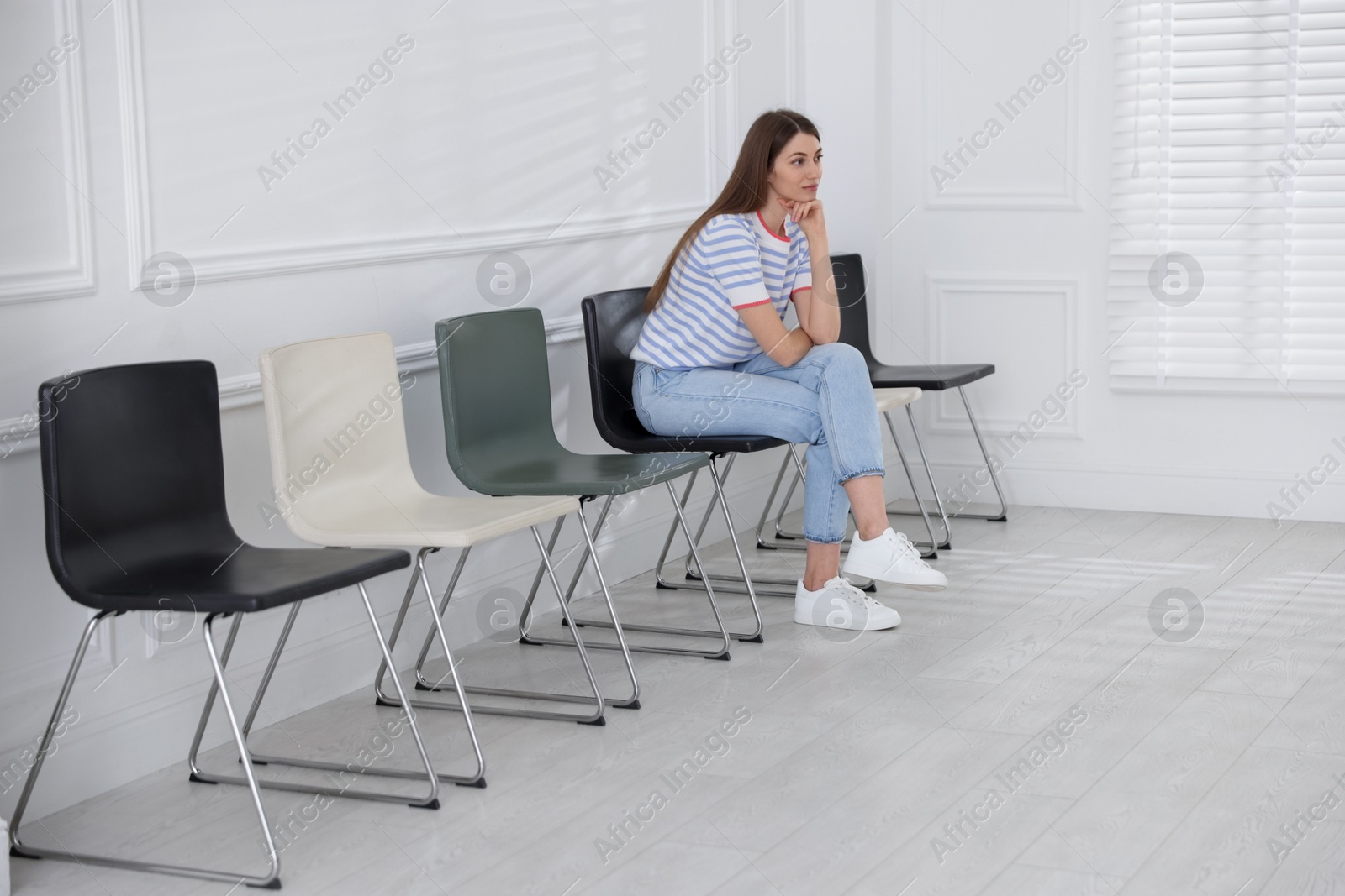 Woman sitting on chair and waiting for appointment indoors Photo of Woman sitting on chair and waiting for appointment indoors