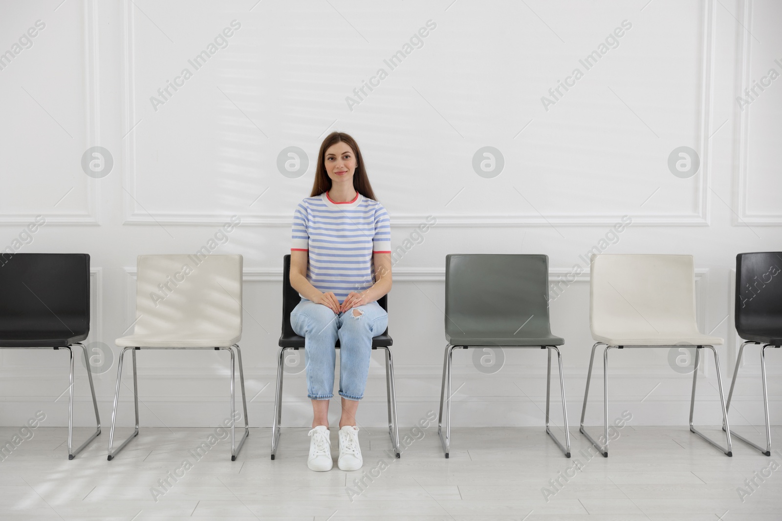 Woman sitting on chair and waiting for appointment indoors Photo of Woman sitting on chair and waiting for appointment indoors