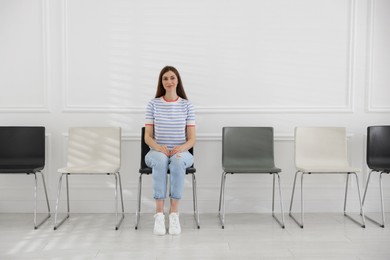 Photo of Woman sitting on chair and waiting for appointment indoors