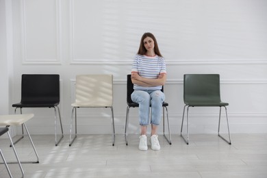 Photo of Woman sitting on chair and waiting for appointment indoors