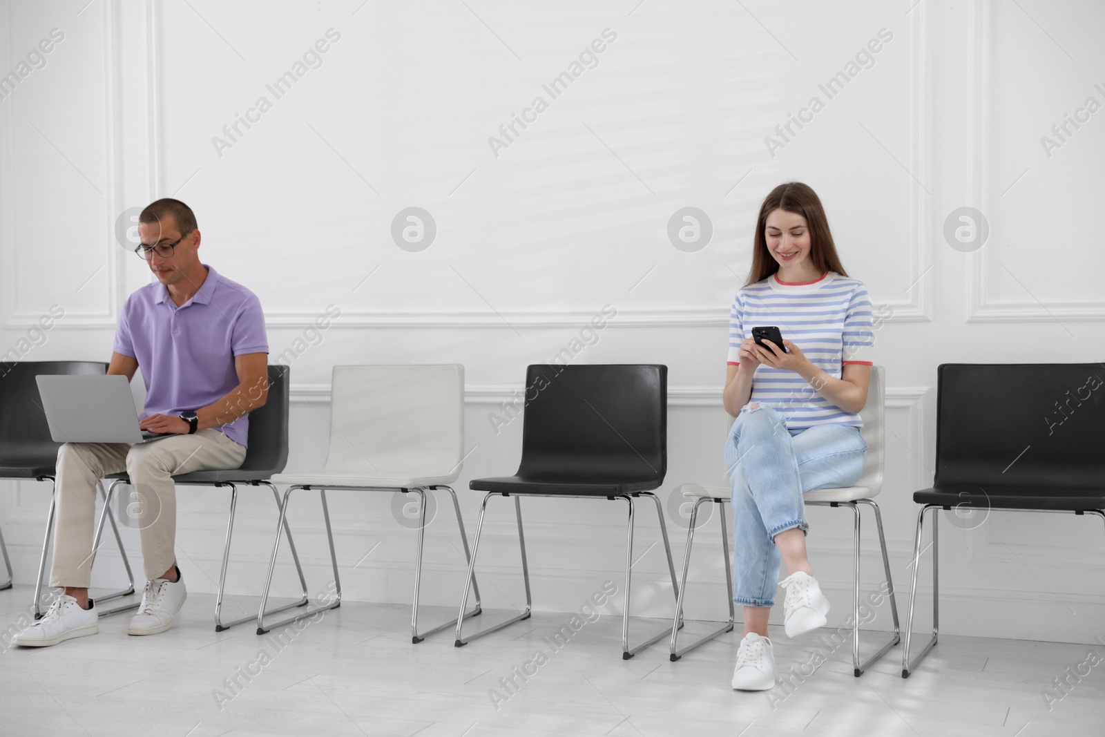 Man and woman waiting for appointment indoors Photo of Man and woman waiting for appointment indoors