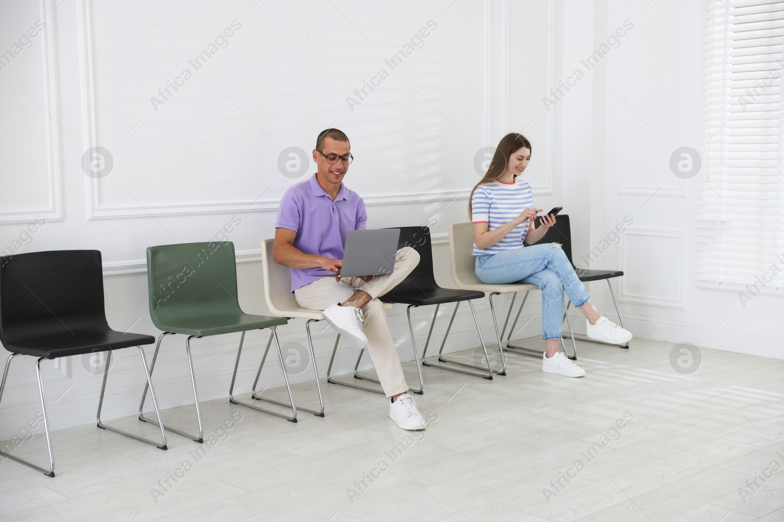 Man and woman waiting for appointment indoors Photo of Man and woman waiting for appointment indoors