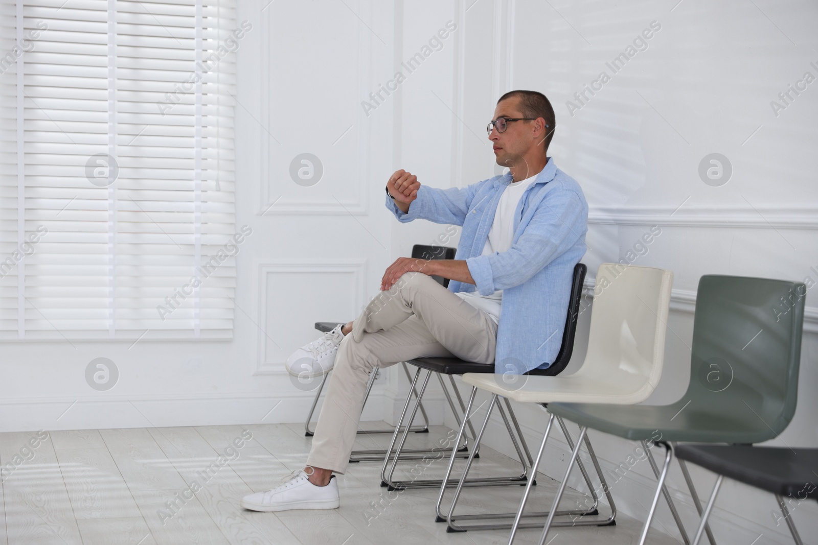 Man looking at wristwatch while waiting for appointment indoors Photo of Man looking at wristwatch while waiting for appointment indoors