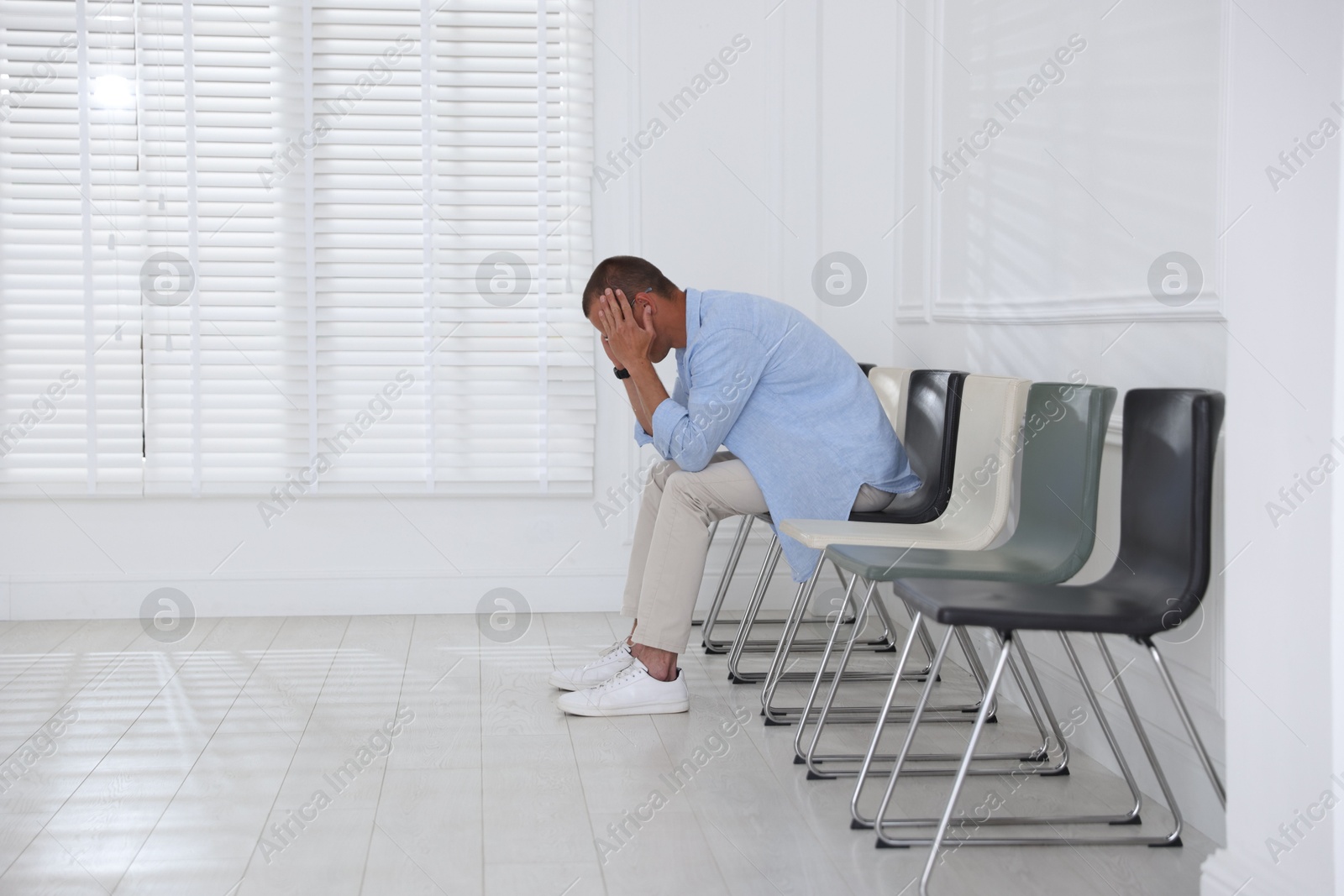 Man sitting on chair and waiting for appointment indoors Photo of Man sitting on chair and waiting for appointment indoors