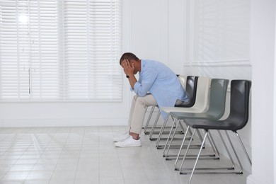 Photo of Man sitting on chair and waiting for appointment indoors