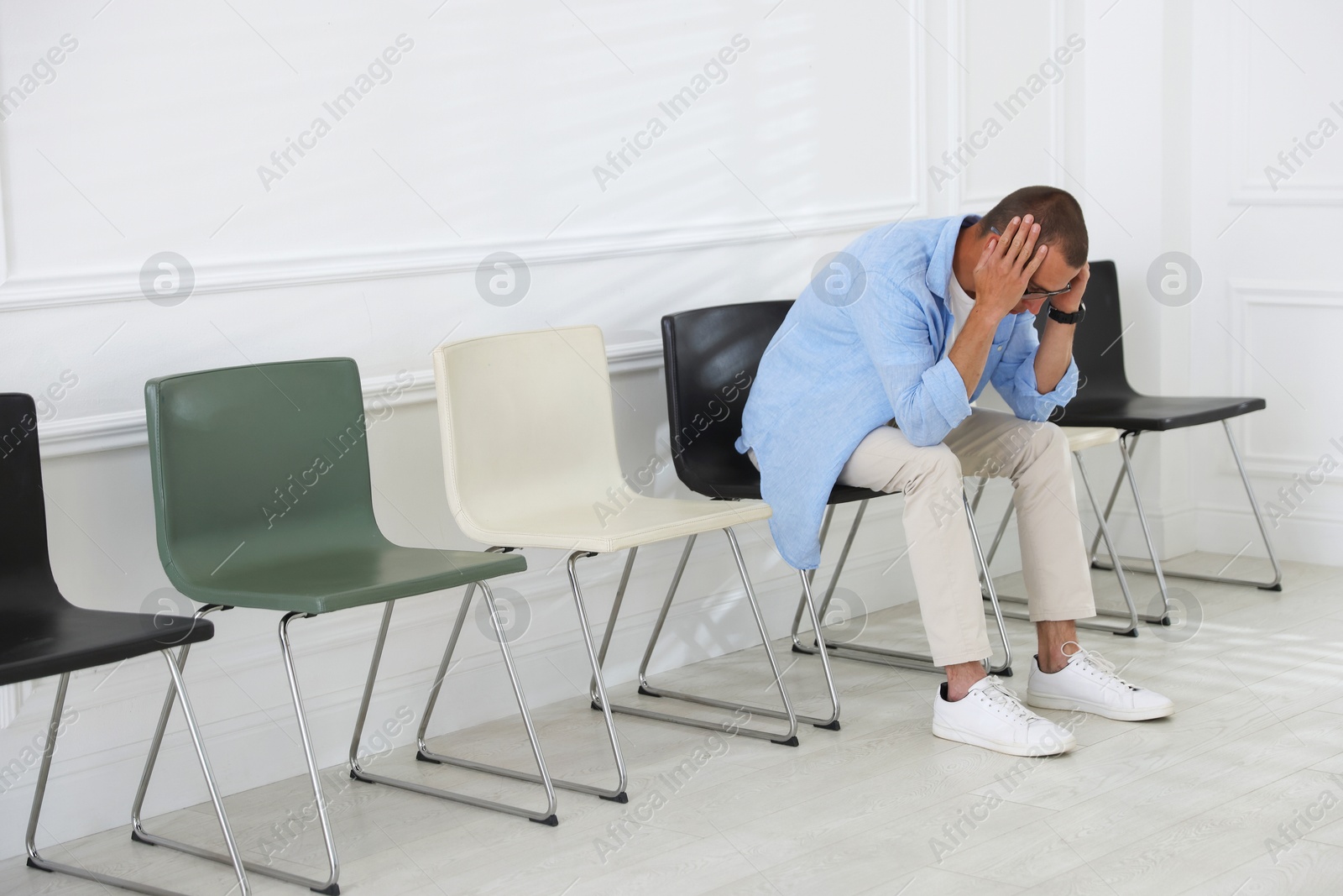 Man sitting on chair and waiting for appointment indoors Photo of Man sitting on chair and waiting for appointment indoors