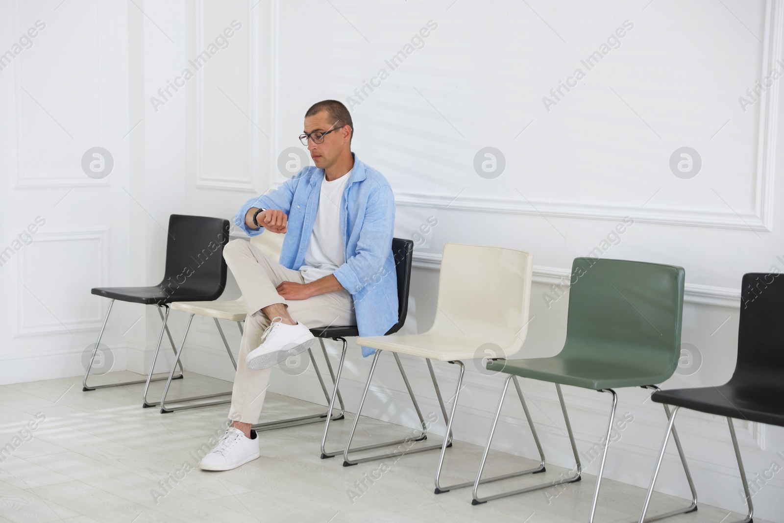 Man looking at wristwatch while waiting for appointment indoors Photo of Man looking at wristwatch while waiting for appointment indoors