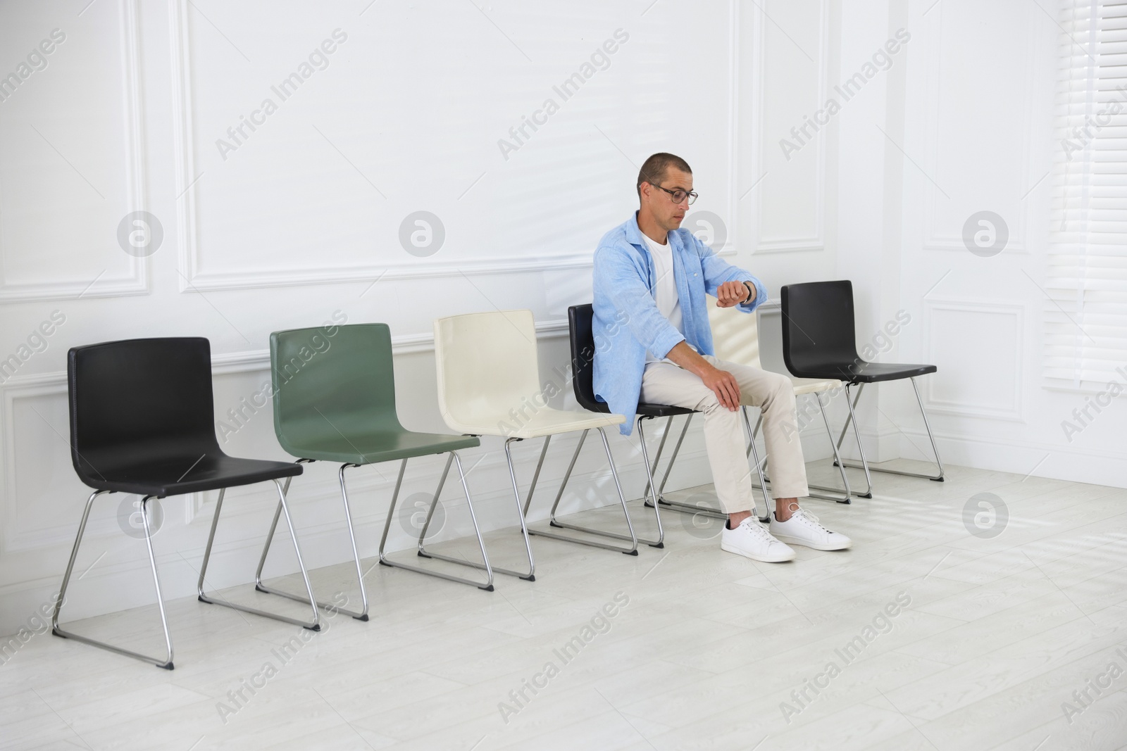 Man looking at wristwatch while waiting for appointment indoors Photo of Man looking at wristwatch while waiting for appointment indoors