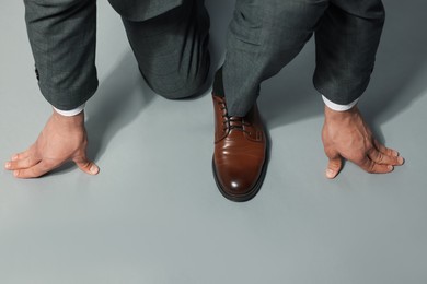 Photo of Businessman in starting position on gray background, top view