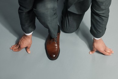 Photo of Businessman in starting position on gray background, top view
