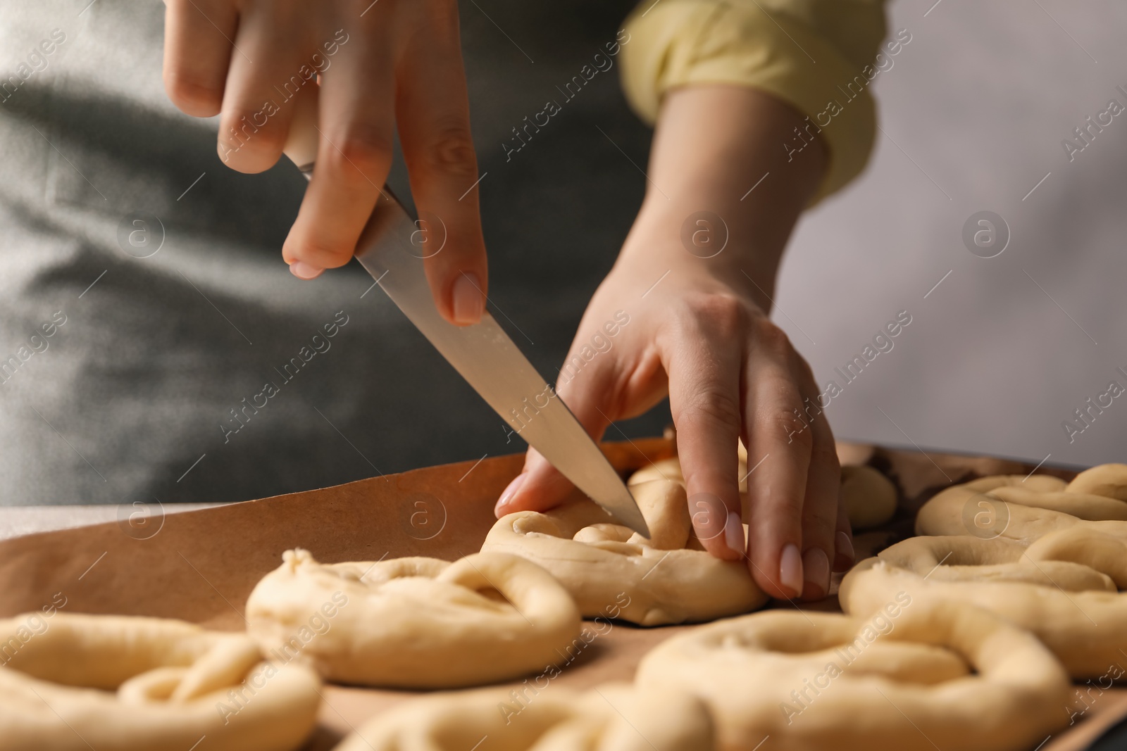 Woman cutting uncooked pretzel at table, closeup Photo of Woman cutting uncooked pretzel at table, closeup