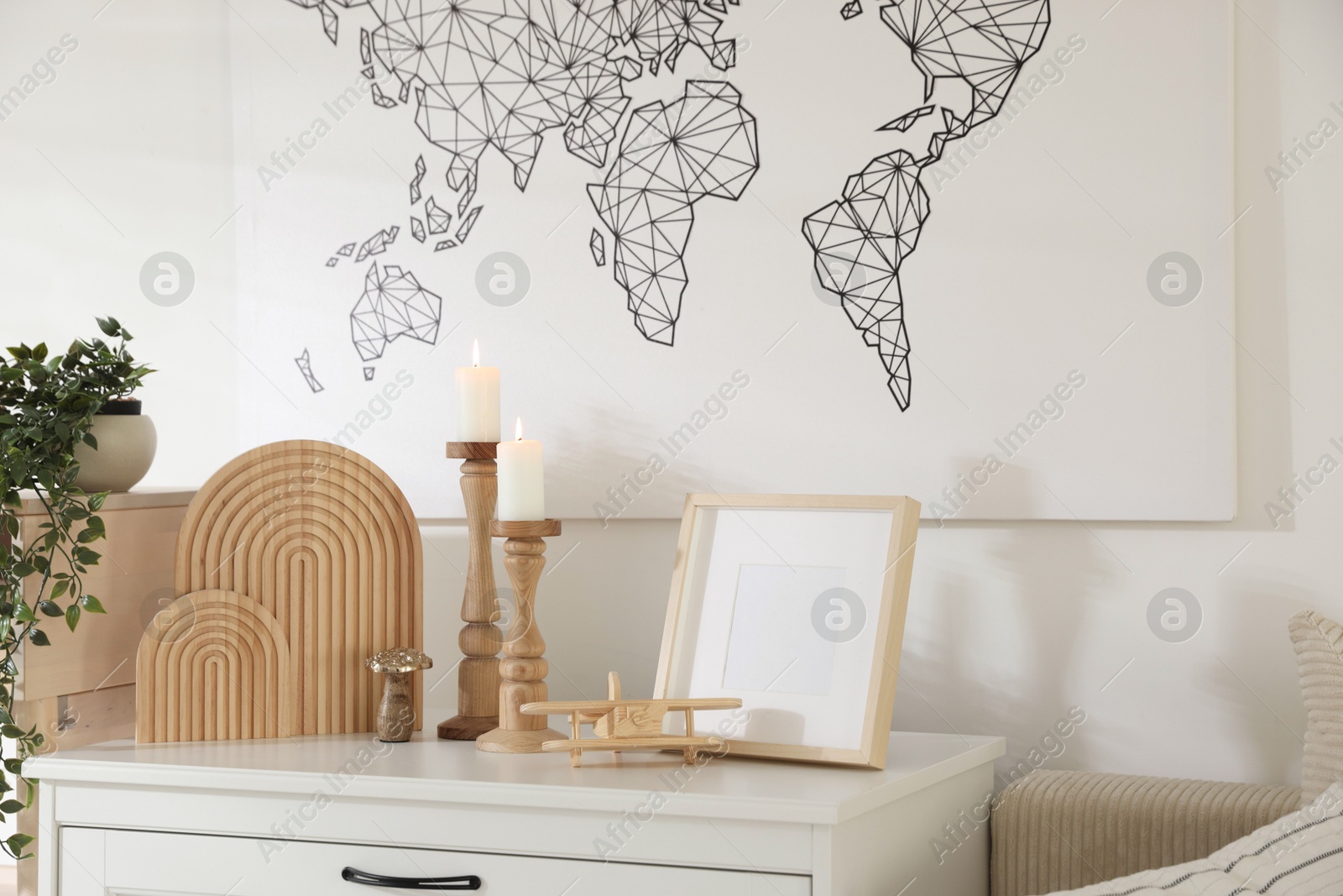 Stylish candlesticks with burning candles and other decor on cabinet near wall indoors Photo of Stylish candlesticks with burning candles and other decor on cabinet near wall indoors