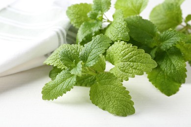 Photo of Fresh lemon balm leaves on white table, closeup