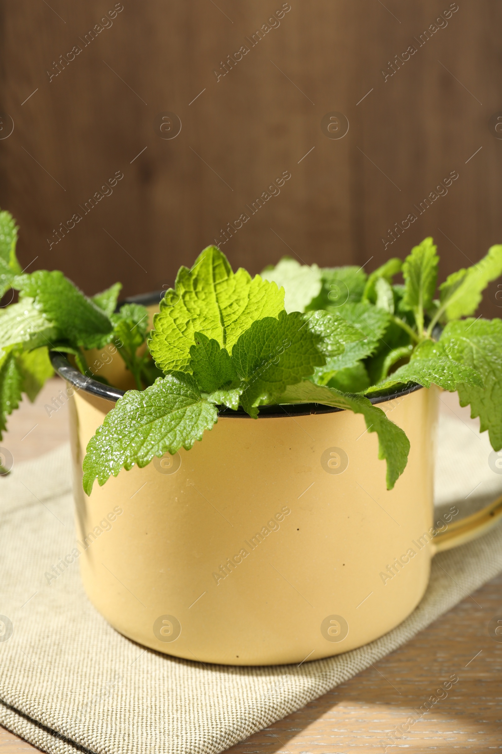 Fresh lemon balm leaves in mug on wooden table, closeup Photo of Fresh lemon balm leaves in mug on wooden table, closeup