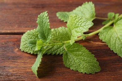 Photo of Fresh lemon balm leaves on wooden table, closeup