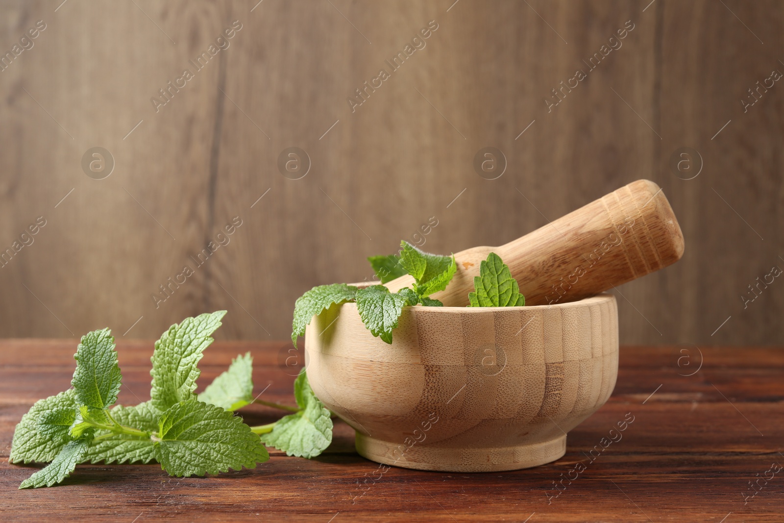 Fresh lemon balm leaves, pestle and mortar on wooden table, closeup Photo of Fresh lemon balm leaves, pestle and mortar on wooden table, closeup