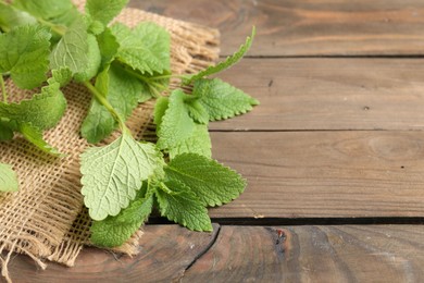 Photo of Fresh lemon balm leaves on wooden table, closeup. Space for text