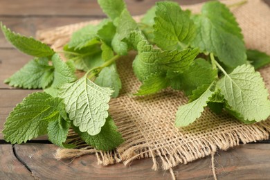 Photo of Fresh lemon balm leaves on wooden table, closeup