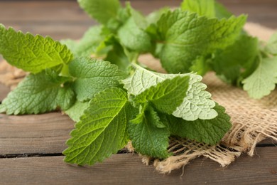 Photo of Fresh lemon balm leaves on wooden table, closeup